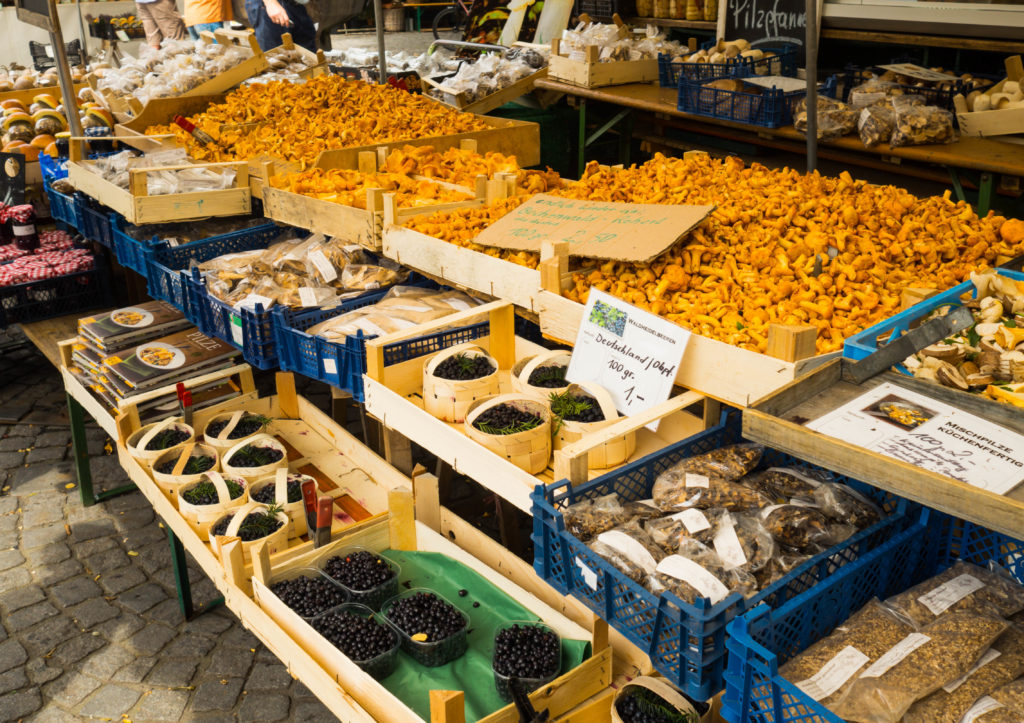 Das Bild zeigt einen typischen Stand auf dem Viktualienmarkt in München mit frischen Heidelbeeren und Pfifferlingen.