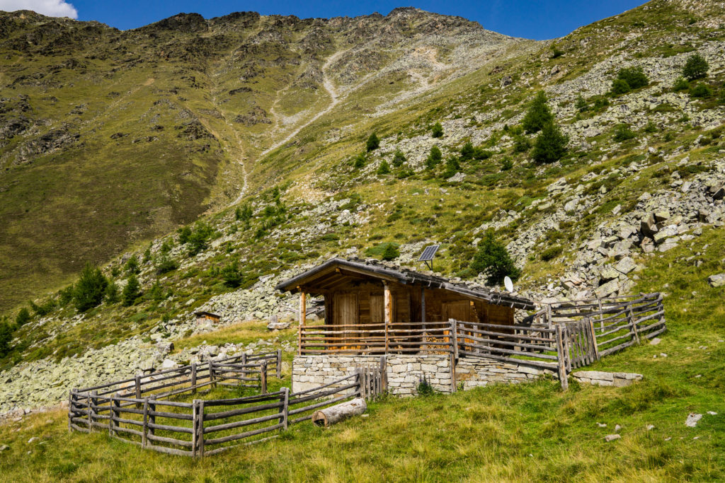 Das Bild zeigt eine Holzhütte vor einem Berg.